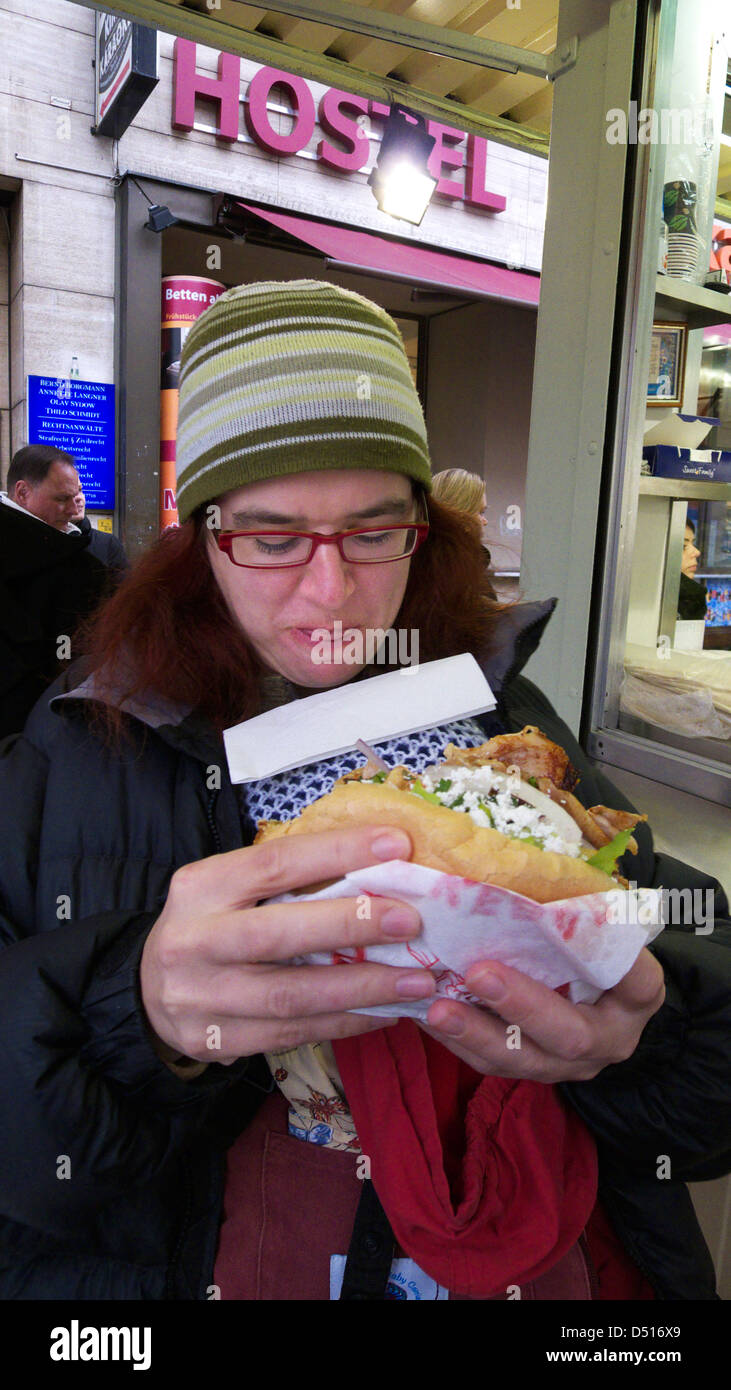 A mother with her baby in a baby carrier scoffing a Mustafa`s kebab in Berlin Stock Photo